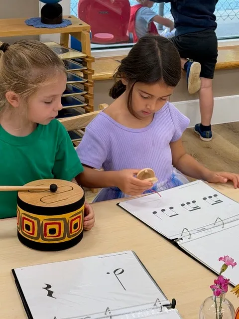Two girls working with a music lesson and sound material at a classroom table